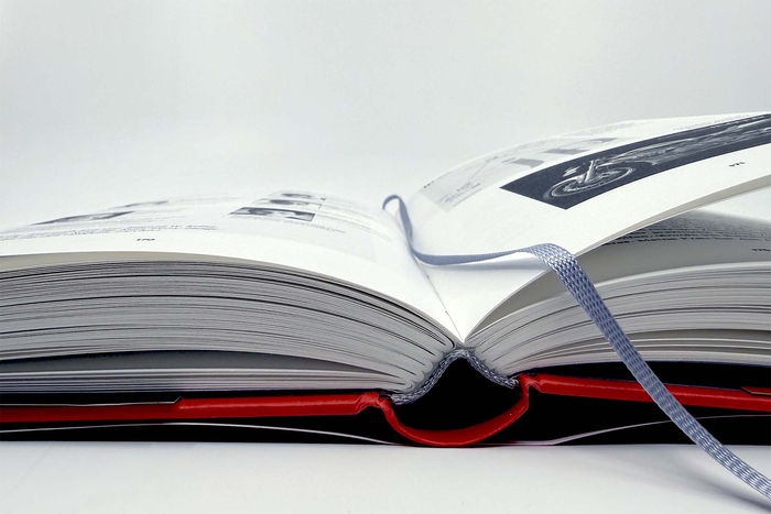 Aufgeschlagenes Buch, gesehen von vorne, mit sichtbarem Lesebändchen zwischen den Seiten.